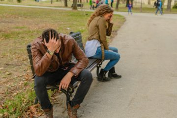 man and woman sitting on bench