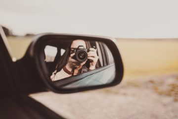 unrecognizable female photographer taking photos and reflecting in rear window