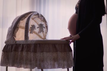 pregnant woman standing near white brown bassinet